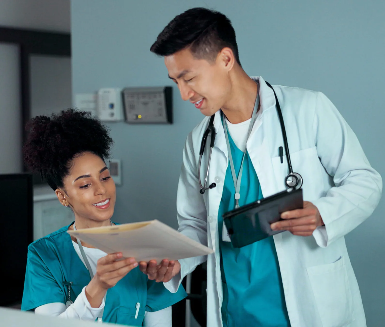 Doctor and Nurse Reviewing Patient Chart and Tablet in Hospital